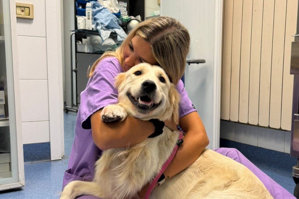Una Dottoressa veterinaria della Clinica Veterinaria Sant'Anna seduta per terra abbraccia un golden retriever